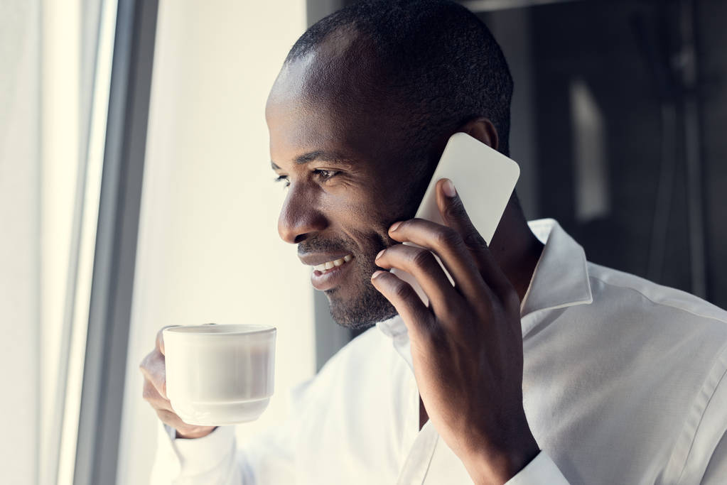 sonriente joven hombre de negocios en camisa blanca hablando por teléfono durante el descanso del café
 - Foto, Imagen