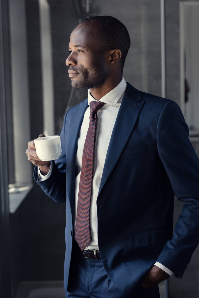 joven hombre de negocios guapo con taza de café mirando hacia otro lado
 - Foto, imagen
