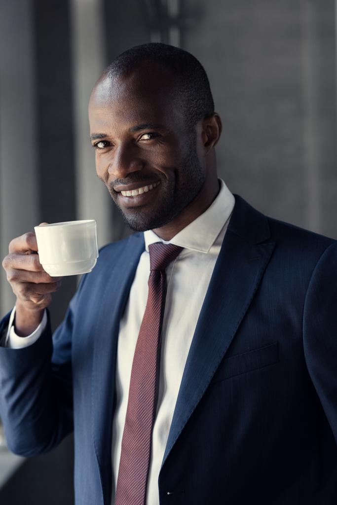 boldog fiatal üzletember csésze kávé látszó-on fényképezőgép - Fotó, kép
