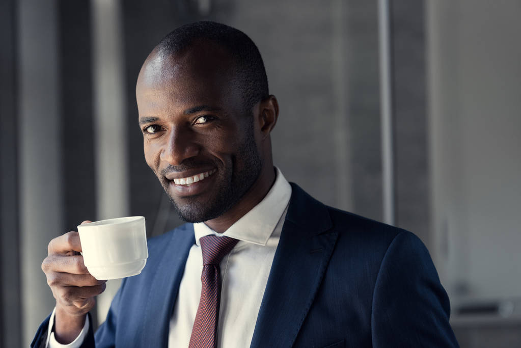 sorridente jovem empresário com xícara de café olhando para a câmera
 - Foto, Imagem