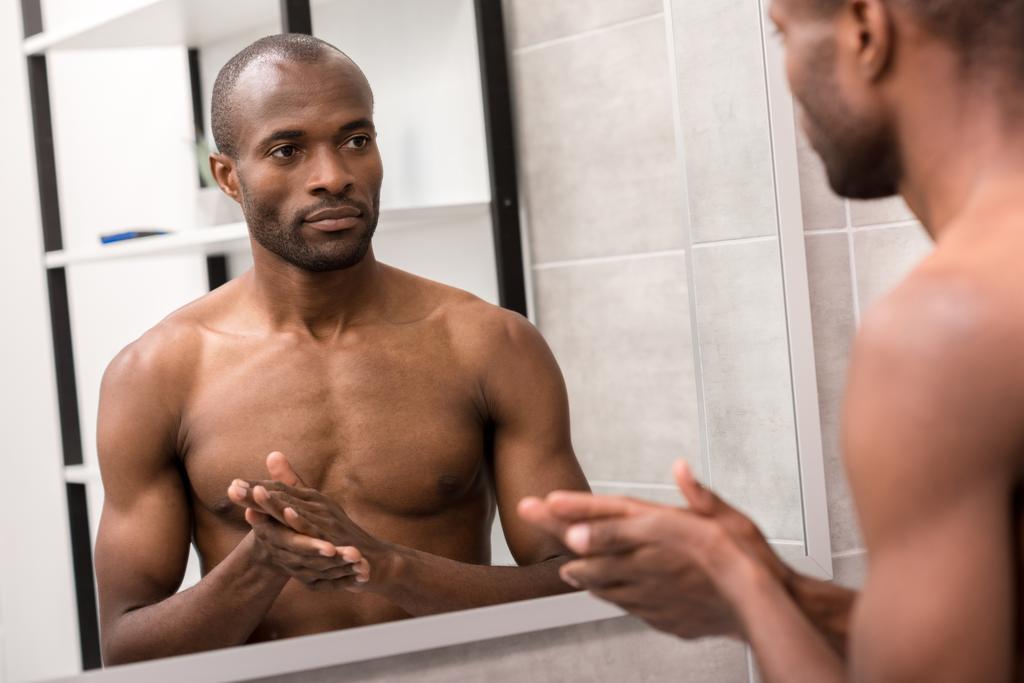 красивый молодой человек смотрит в зеркало в ванной комнате
 - Фото, изображение