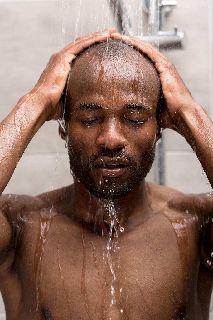 handsome young african american man washing in shower with closed eyes  - Photo, Image