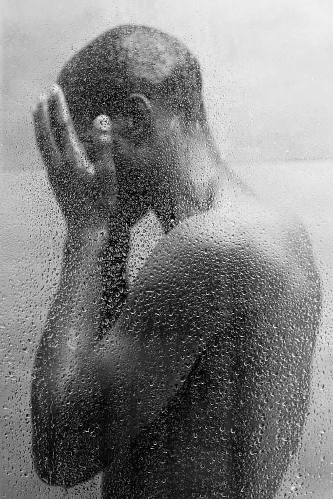 side view of young african american man washing body in shower, black and white photo - Photo, Image