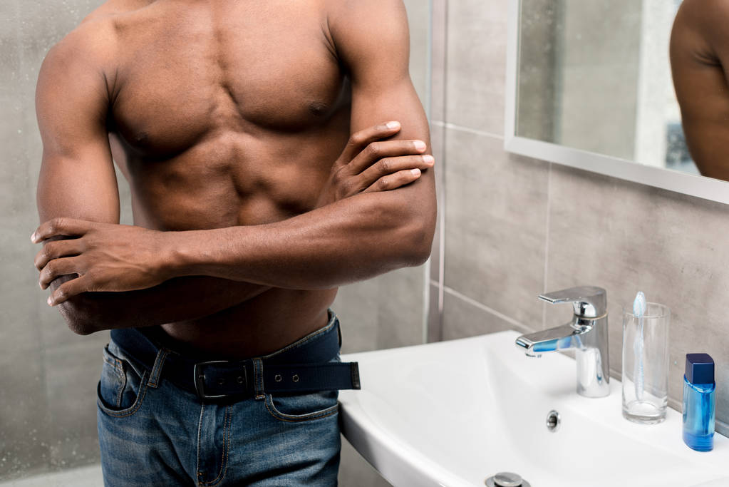περικοπεί shot από νεαρός αφρικανική αμερικανική άνθρωπος που στέκεται με σταυρωμένα τα χέρια στο μπάνιο - Φωτογραφία, εικόνα