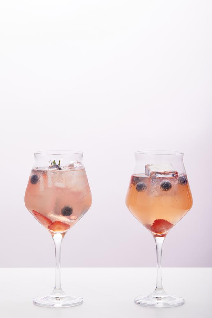 δύο ποτήρια αναψυκτικού με παγάκια, δενδρολίβανο, φράουλες και βατόμουρα που απομονώνονται σε γκρι φόντο  - Φωτογραφία, εικόνα