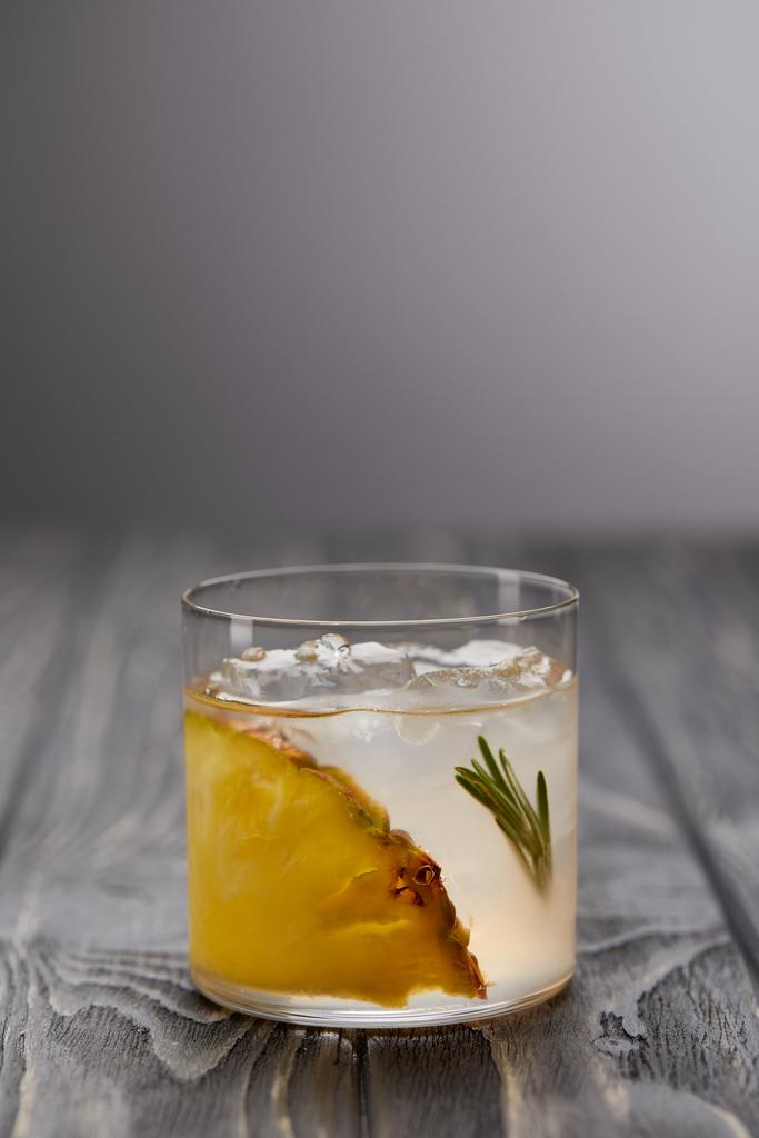 glas limonade met rozemarijn, ijsblokjes en ananas op grijs houten tafel - Foto, afbeelding