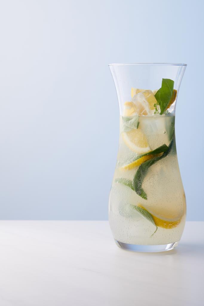 jarro de limonada com folhas de hortelã, cubos de gelo e fatias de limão no fundo azul
  - Foto, Imagem