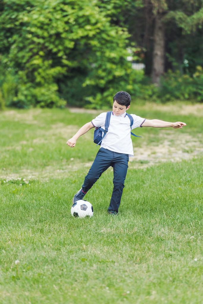 активный ребенок играет с футбольным мячом на траве
 - Фото, изображение