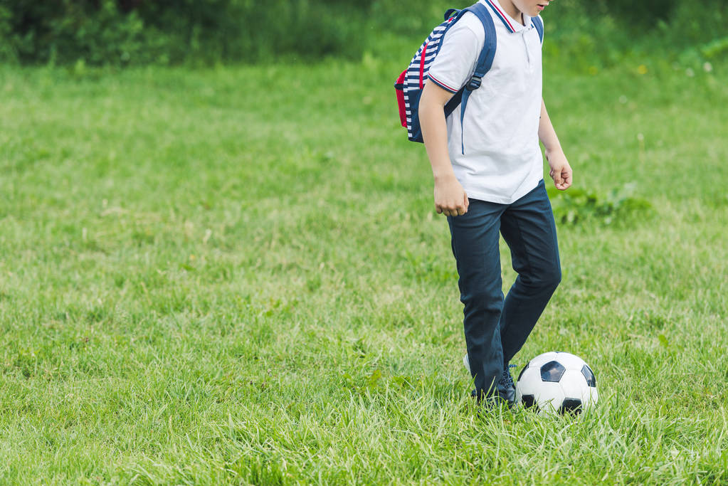 rajattu laukaus lapsi pelaa jalkapalloa nurmikentällä
 - Valokuva, kuva