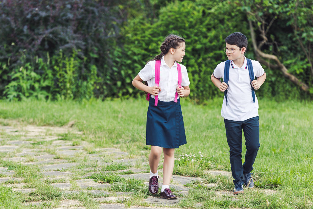 adorable dzieci w wieku szkolnym chodzenie przez ścieżki w parku razem - Zdjęcie, obraz