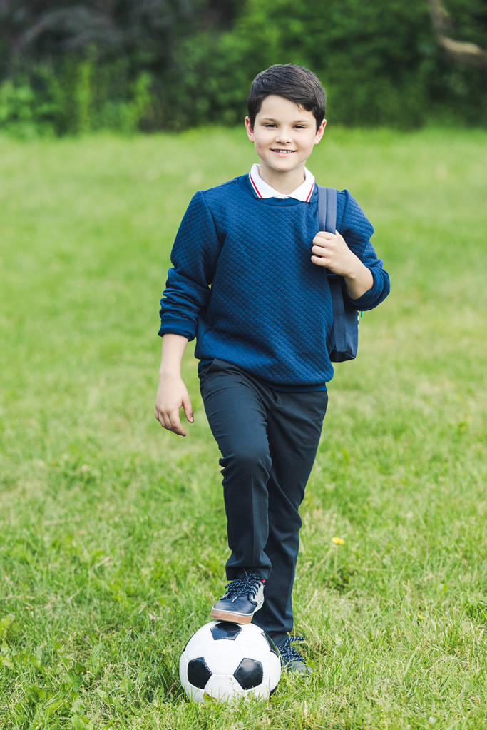 futbol topu ve sırt çantası çim sahada sevimli çocukla - Fotoğraf, Görsel
