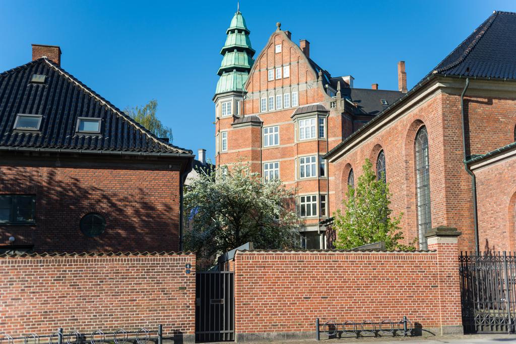 Ziegelmauer, Kirche und Häuser an sonnigen Tagen in Kopenhagen, Dänemark - Foto, Bild