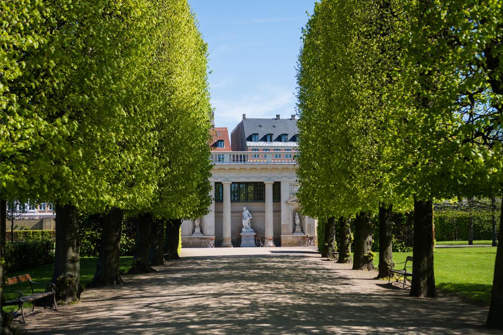 beco bonito com árvores verdes e edifício histórico com colunas e estátuas em copenhagen, denmark
 - Foto, Imagem