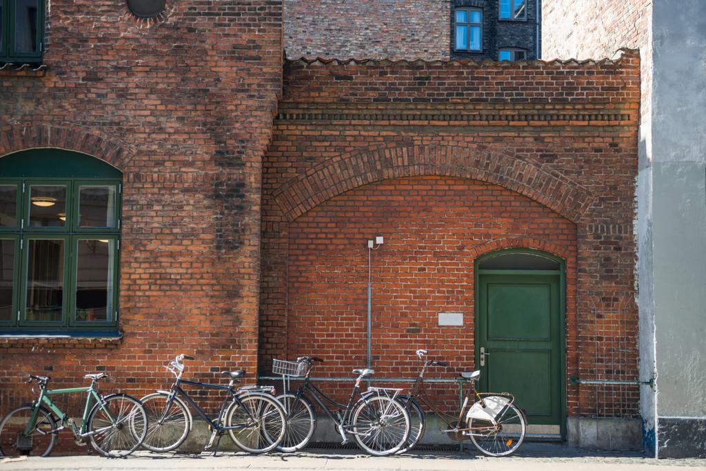 pysäköityjä polkupyöriä lähellä tiiliseinää Kööpenhaminassa, Tanskassa
 - Valokuva, kuva