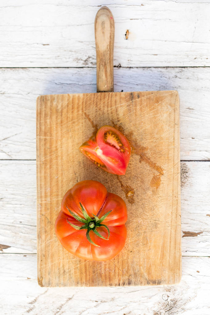 Ώριμη ντομάτα σε ξύλο κοπής στο παλιό ξύλινο τραπέζι - Φωτογραφία, εικόνα