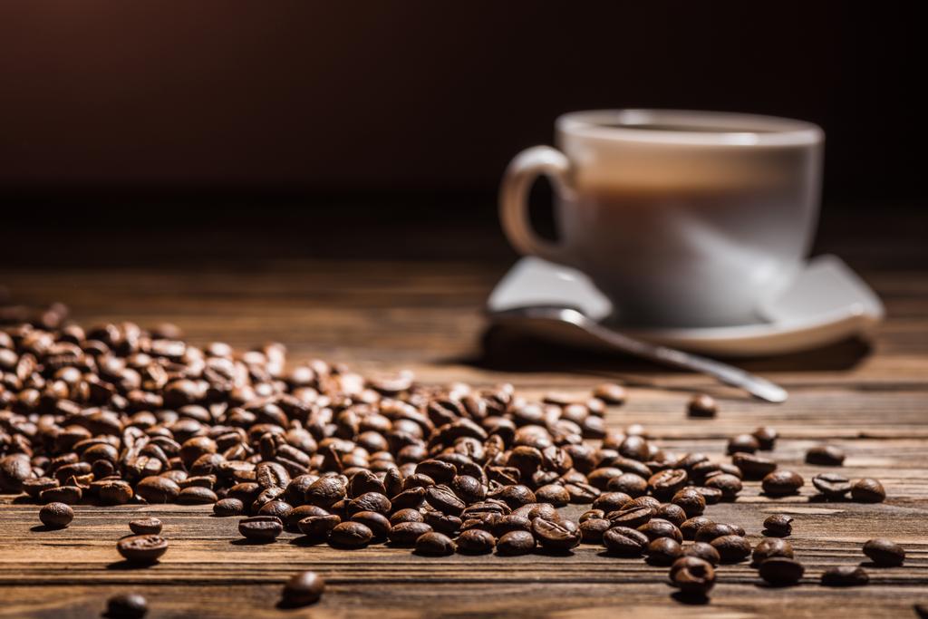 xícara de café na mesa de madeira rústica com grãos de café derramados
 - Foto, Imagem