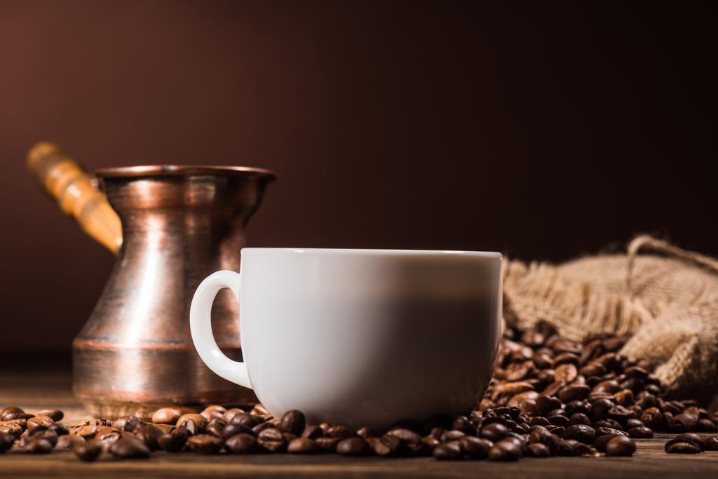 close-up shot of cup of coffee with roasted beans and vintage cezve - Photo, Image
