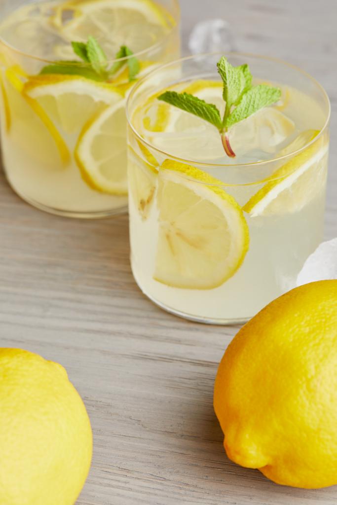 primer plano de vasos de limonada con limones maduros en superficie de madera
  - Foto, imagen