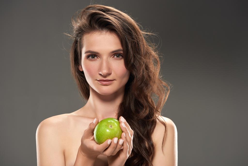 красивая брюнетка со свежим зеленым яблоком, изолированная на сером
 - Фото, изображение