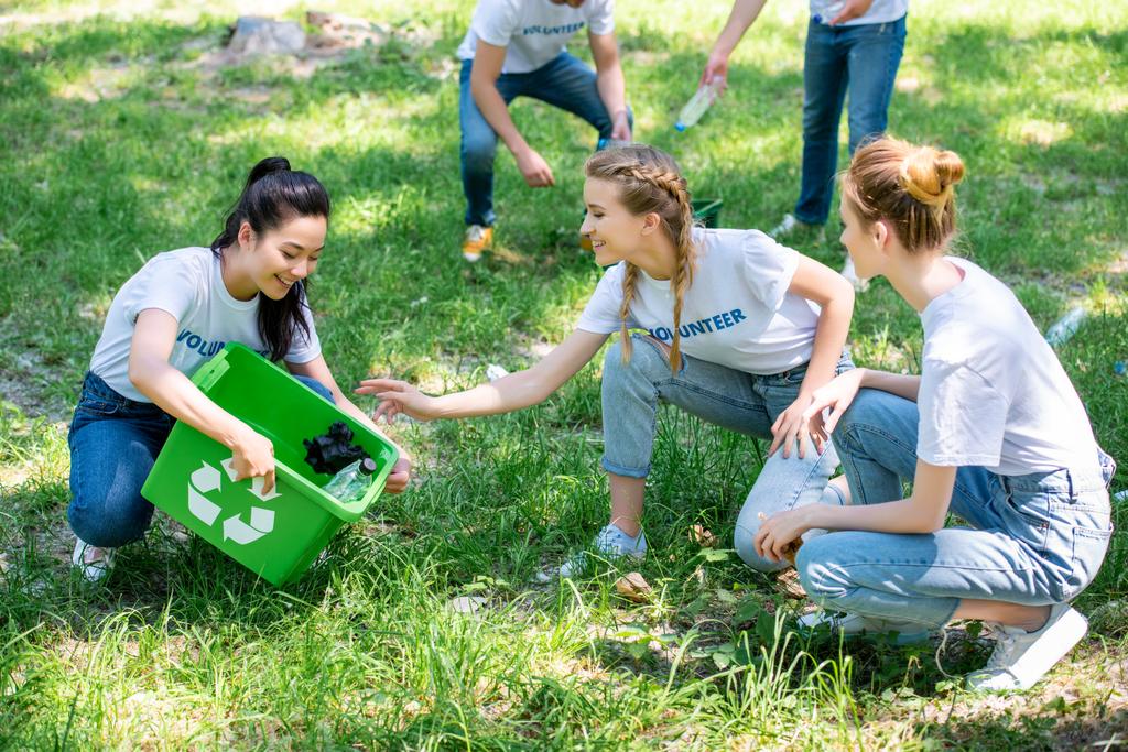 молодые добровольцы чистят зеленую лужайку в парке вместе
 - Фото, изображение