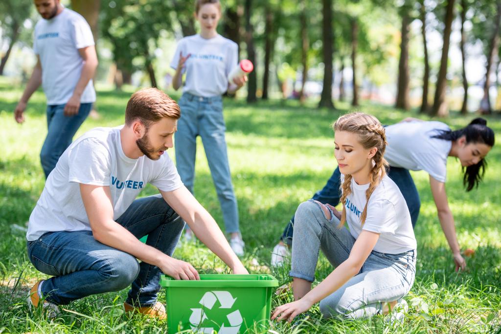 молодые волонтеры чистят газоны с зеленой коробкой для переработки
 - Фото, изображение