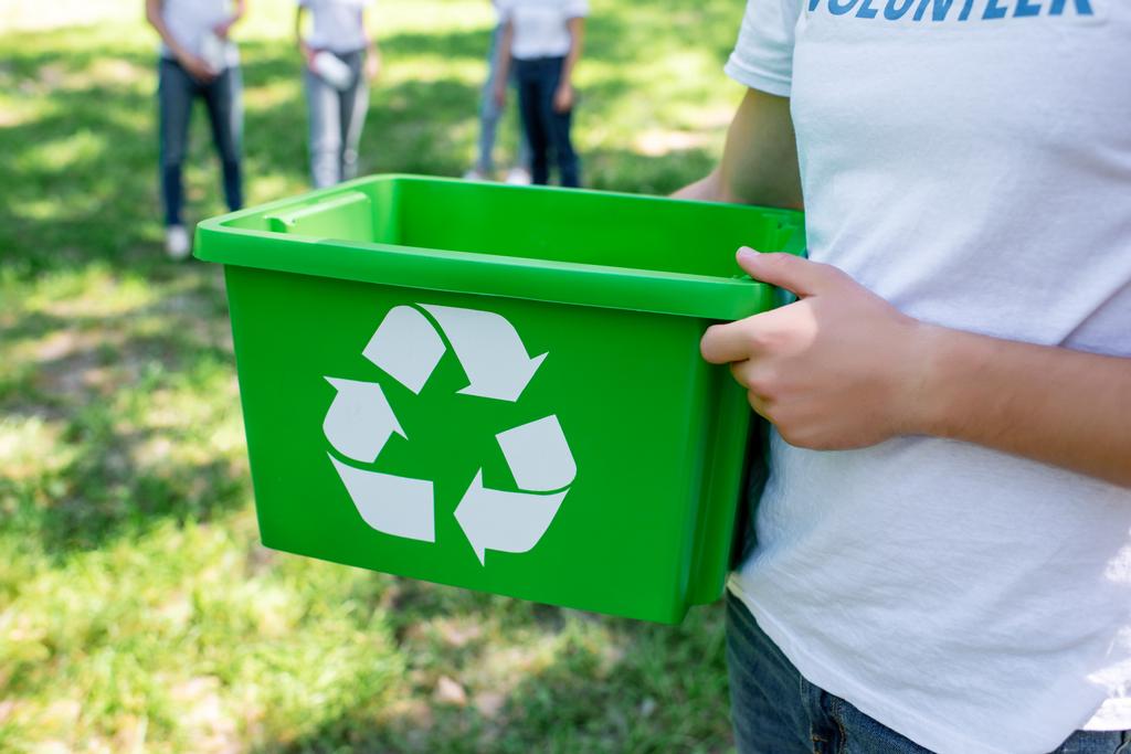 обрезанный вид волонтера, держащего зеленую коробку для утилизации в парке
   - Фото, изображение