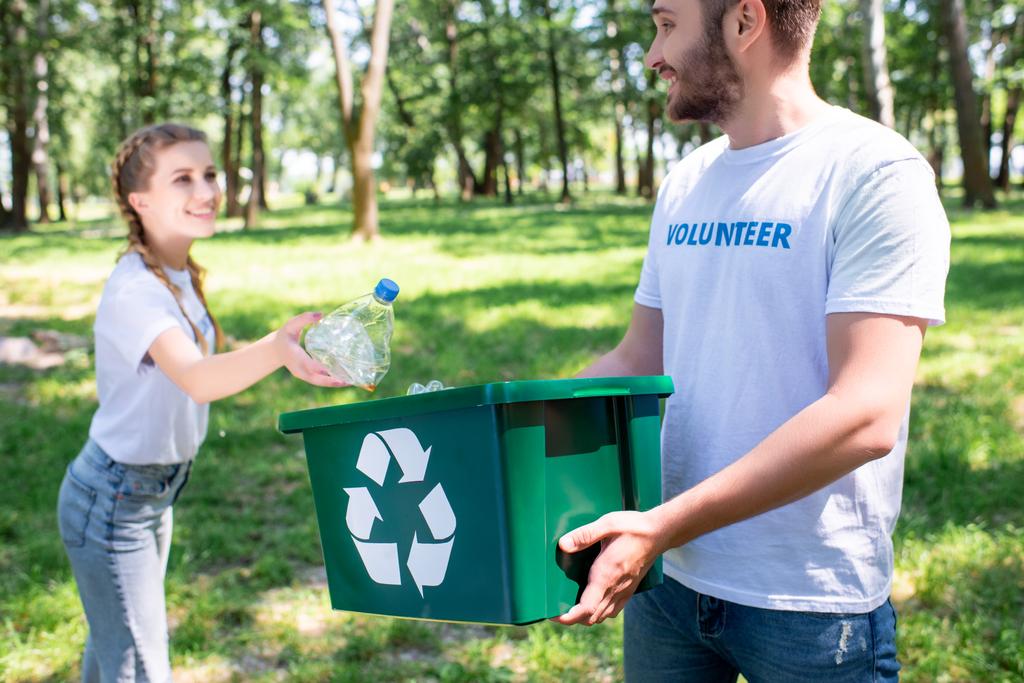jovem casal de voluntários com parque de limpeza caixa de reciclagem verde
  - Foto, Imagem