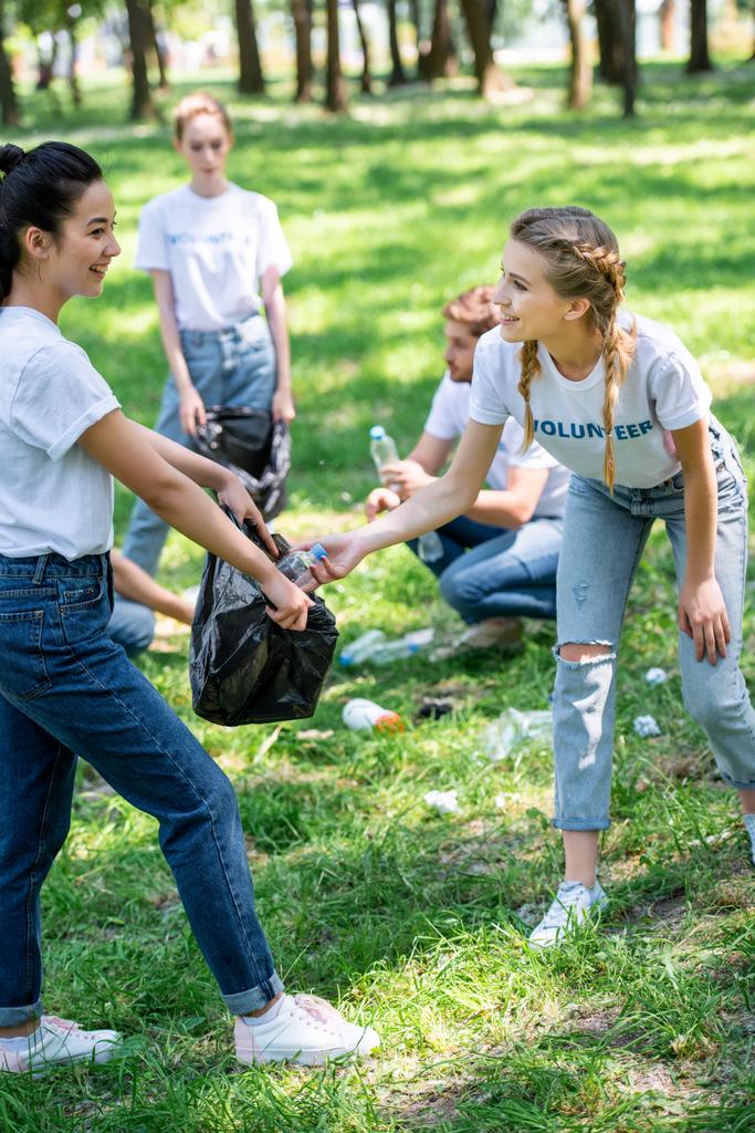 jonge vrijwilligers schoonmaak grasveld in het park samen - Foto, afbeelding