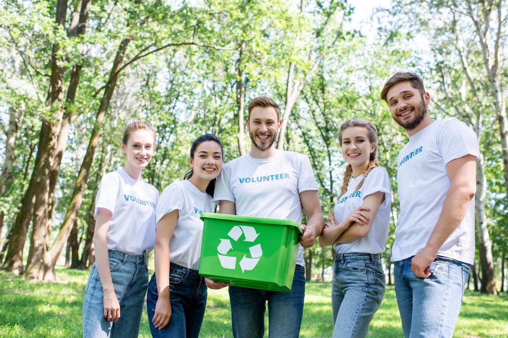young happy volunteers with green recycling box in park  - Photo, Image