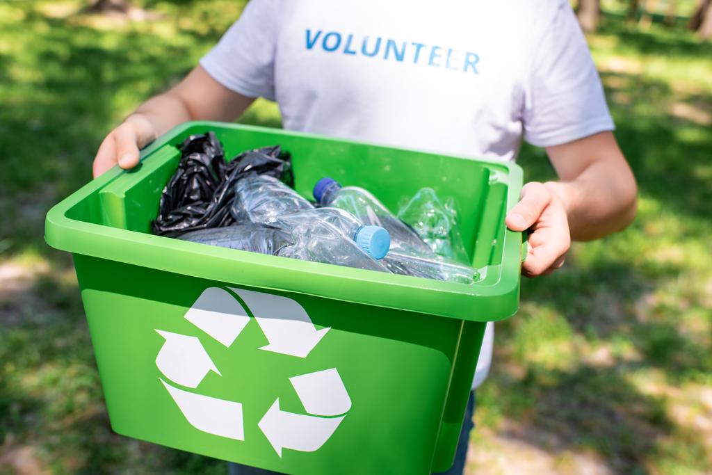 bijgesneden weergave van vrijwilliger bedrijf recycling doos met plastic afval - Foto, afbeelding