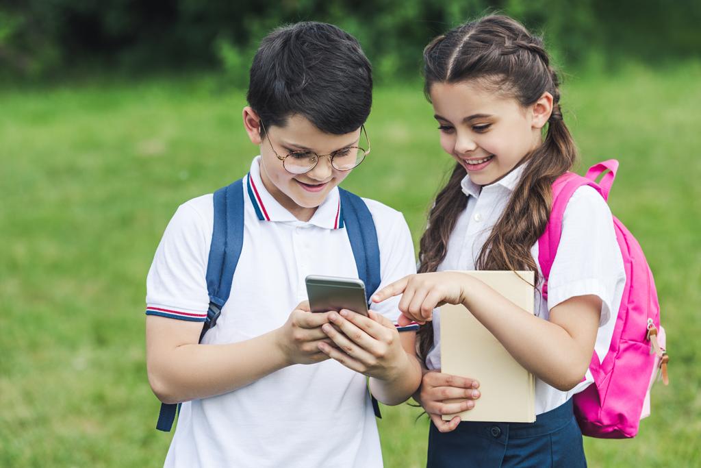 adorables écoliers utilisant smartphone à l'extérieur ensemble
 - Photo, image