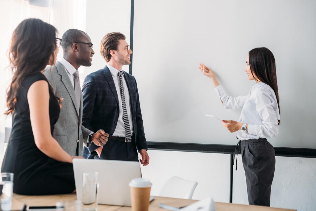 empresários multiculturais olhando para o conselho branco vazio durante reunião de negócios no escritório
 - Foto, Imagem