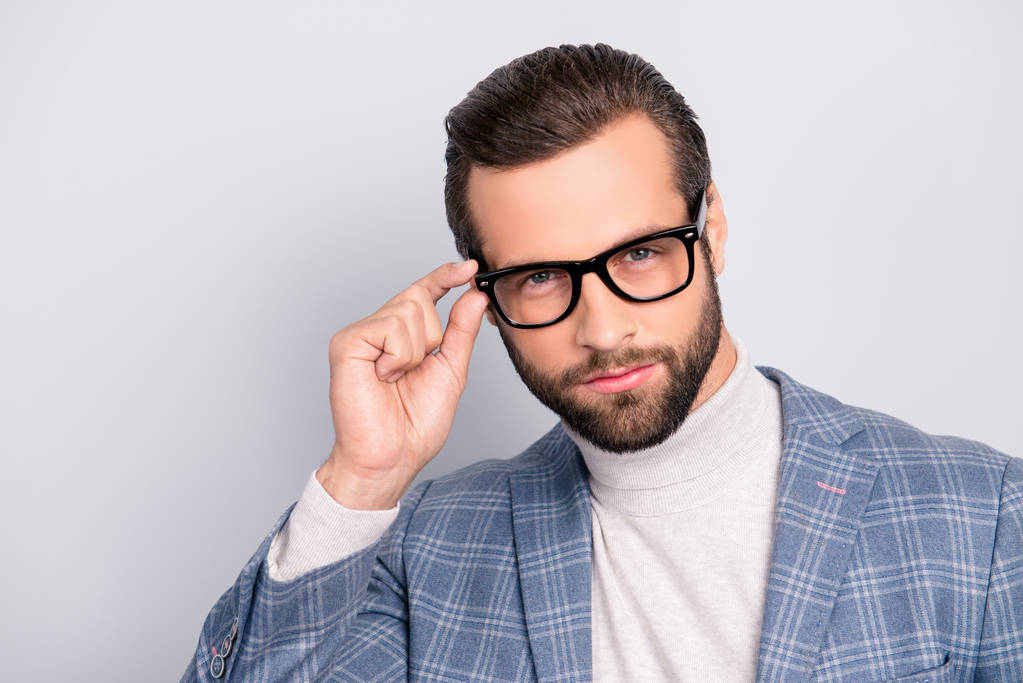 Portrait of gentlemen, manly, stunning, dreamy, inteligent man holding eyelet of glasses on his face with fingers, looking at camera over gray background - Photo, Image