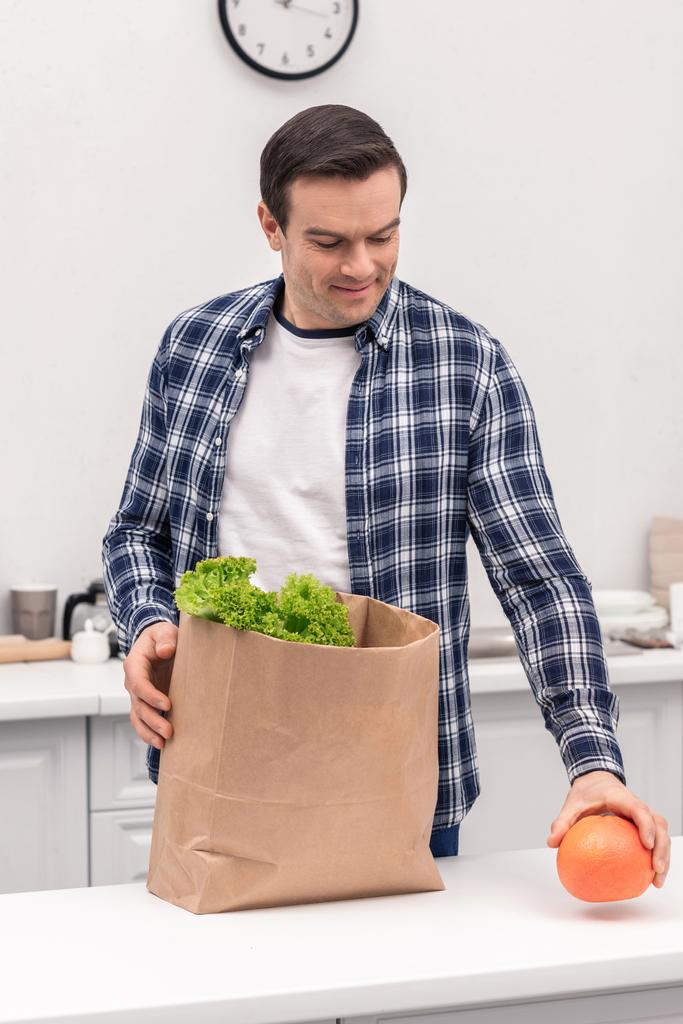 homem adulto feliz desembalagem supermercado saco de papel na cozinha
 - Foto, Imagem