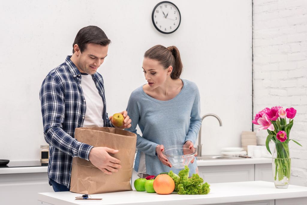 sorprendido pareja adulta desembalaje bolsa de papel después de compras de comestibles
 - Foto, imagen