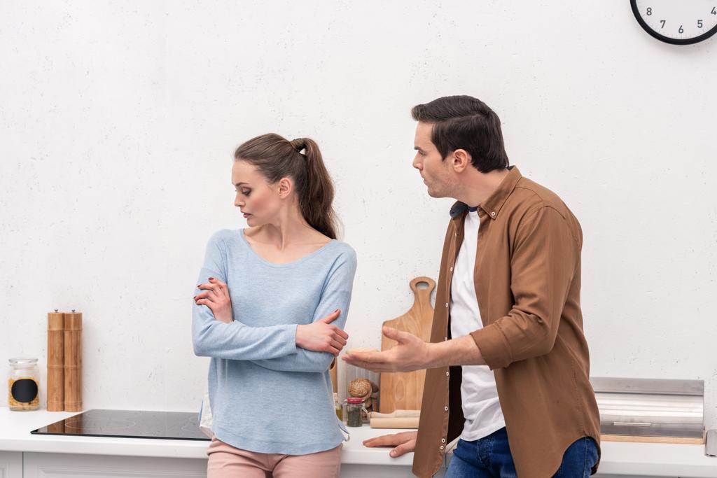 šílený dospělý muž dívá na ženu, zatímco ona ho ignoruje po hádce v kuchyni - Fotografie, Obrázek