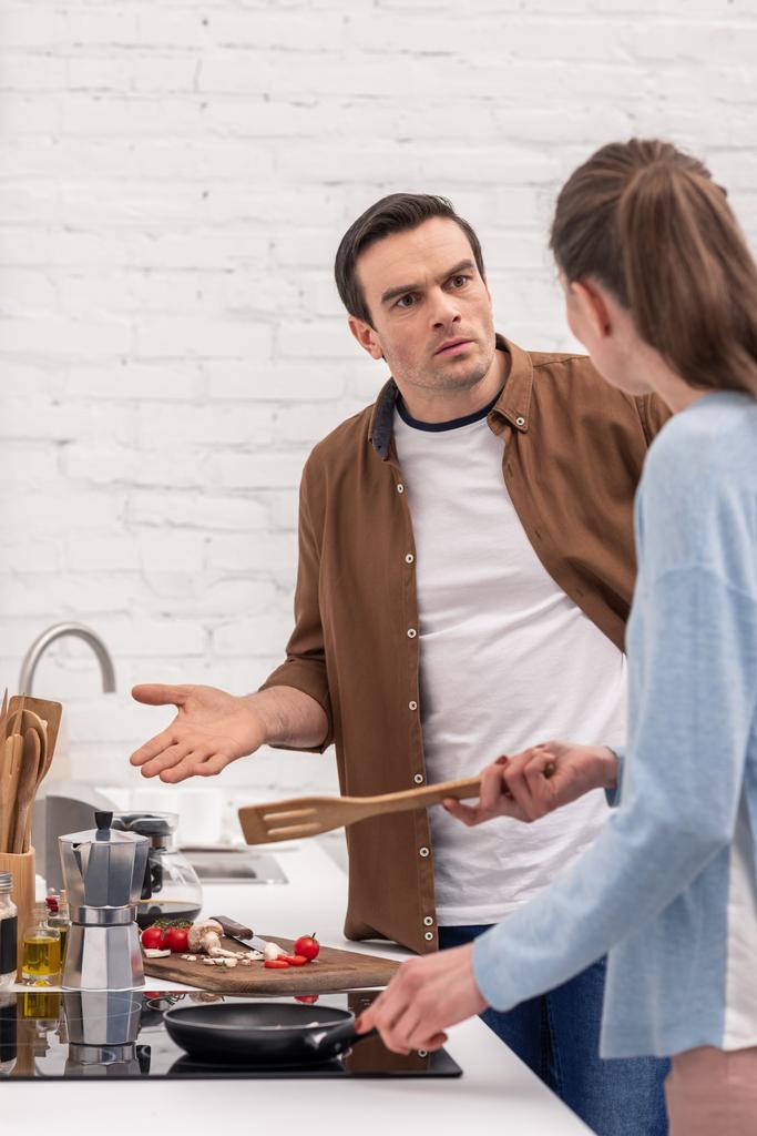 pareja adulta discutiendo en la cocina asegurando mientras prepara la cena
 - Foto, imagen