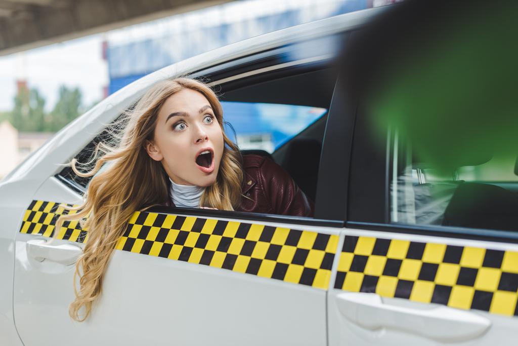Gezielter Fokus eines schockierten Mädchens, das durch das Taxifenster wegschaut  - Foto, Bild