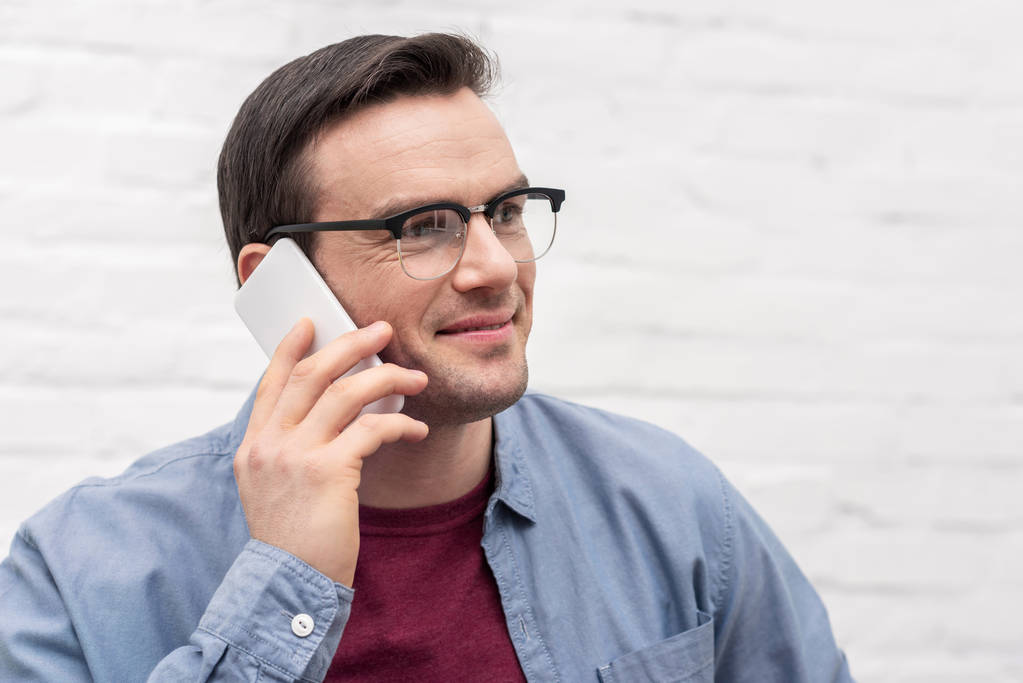 крупним планом портрет щасливого дорослого чоловіка, який розмовляє по телефону перед білою цегляною стіною
 - Фото, зображення