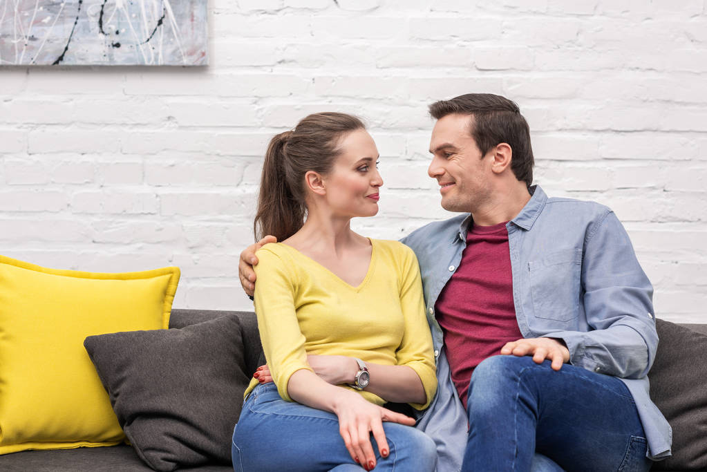 красива доросла пара сидить на дивані вдома і дивиться один на одного щасливо
 - Фото, зображення