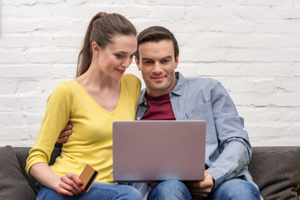 gelukkige volwassen paar waardoor e-winkelen met laptop en creditcard op Bank thuis - Foto, afbeelding