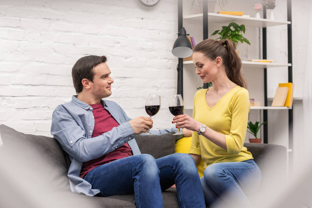volwassen paar glimlachend met glazen rode wijn tijd doorbrengen samen thuis - Foto, afbeelding