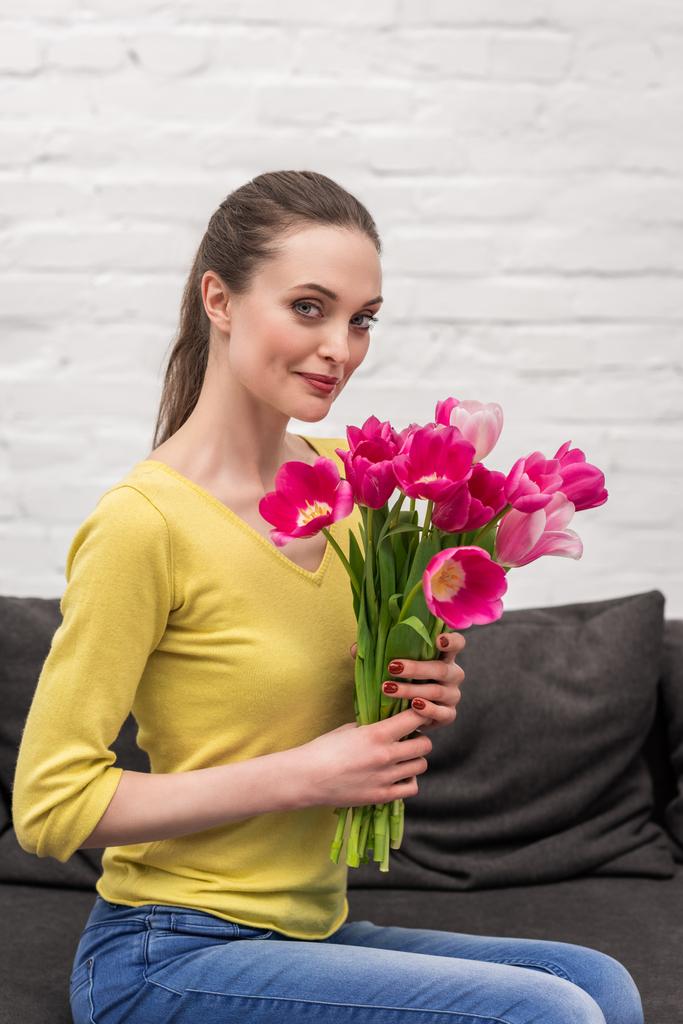 atractiva mujer adulta sosteniendo tulipanes rosa ramo y mirando a la cámara
 - Foto, imagen