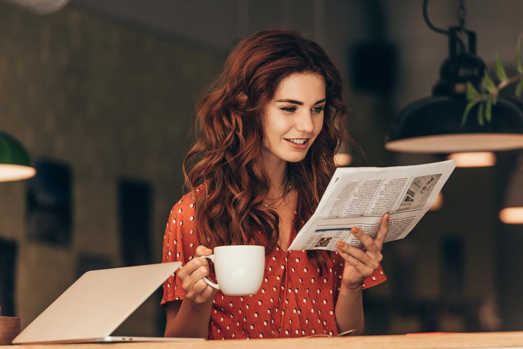 portrait de femme avec tasse de café lecture journal à table avec ordinateur portable dans le café
 - Photo, image