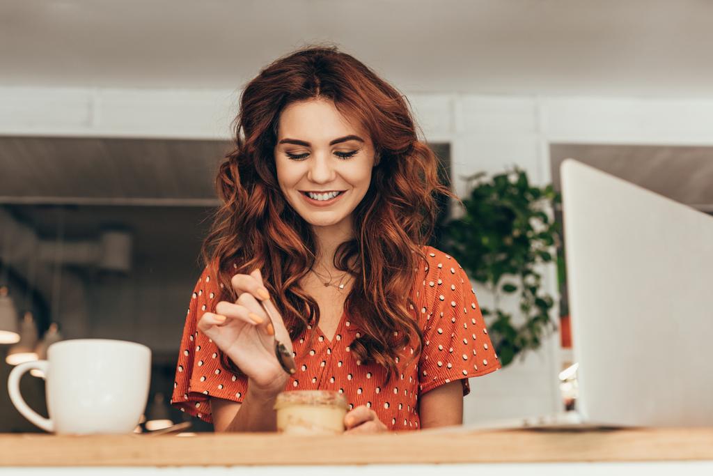 retrato de mulher sorridente comendo saboroso souffle no café
 - Foto, Imagem