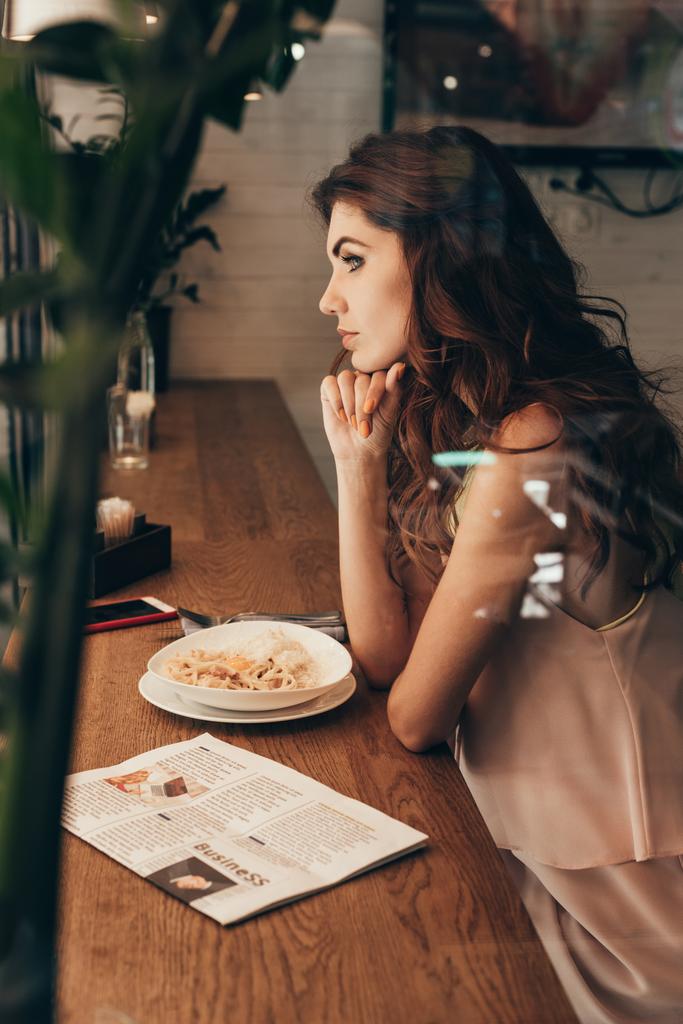 вид сбоку на женщину, сидящую за столом в кафе
 - Фото, изображение