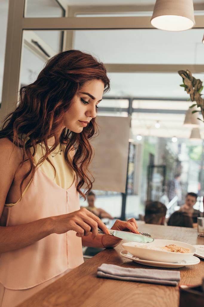 Widok z boku młodej kobiety jedzenie Włoskie makarony w kawiarni - Zdjęcie, obraz