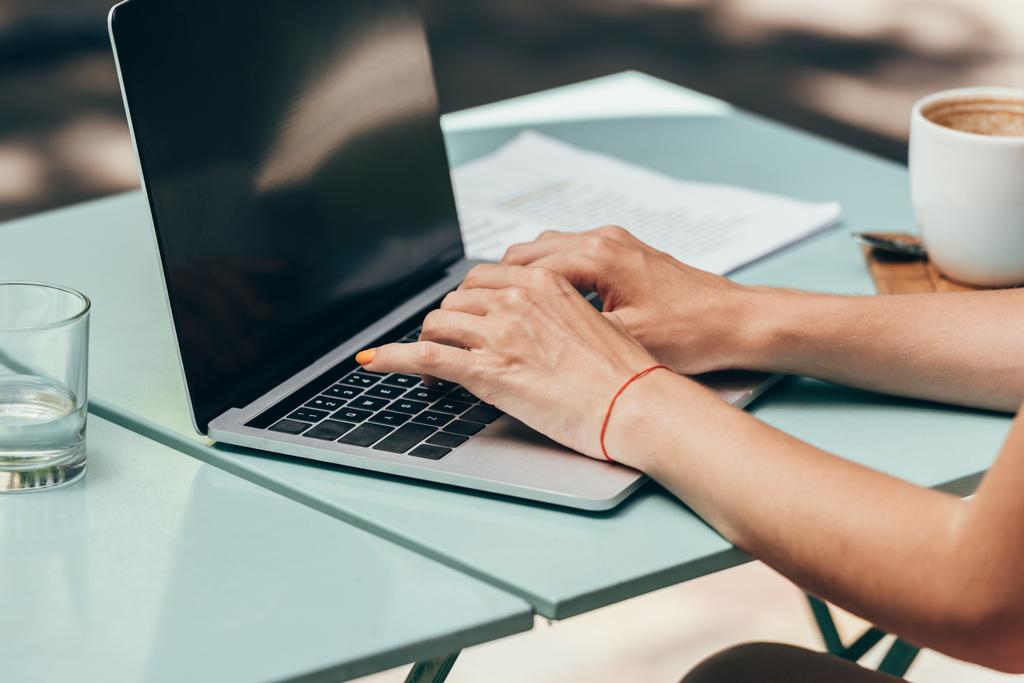 обрезанный снимок деловой женщины, работающей на ноутбуке с пустым экраном в кафе
 - Фото, изображение