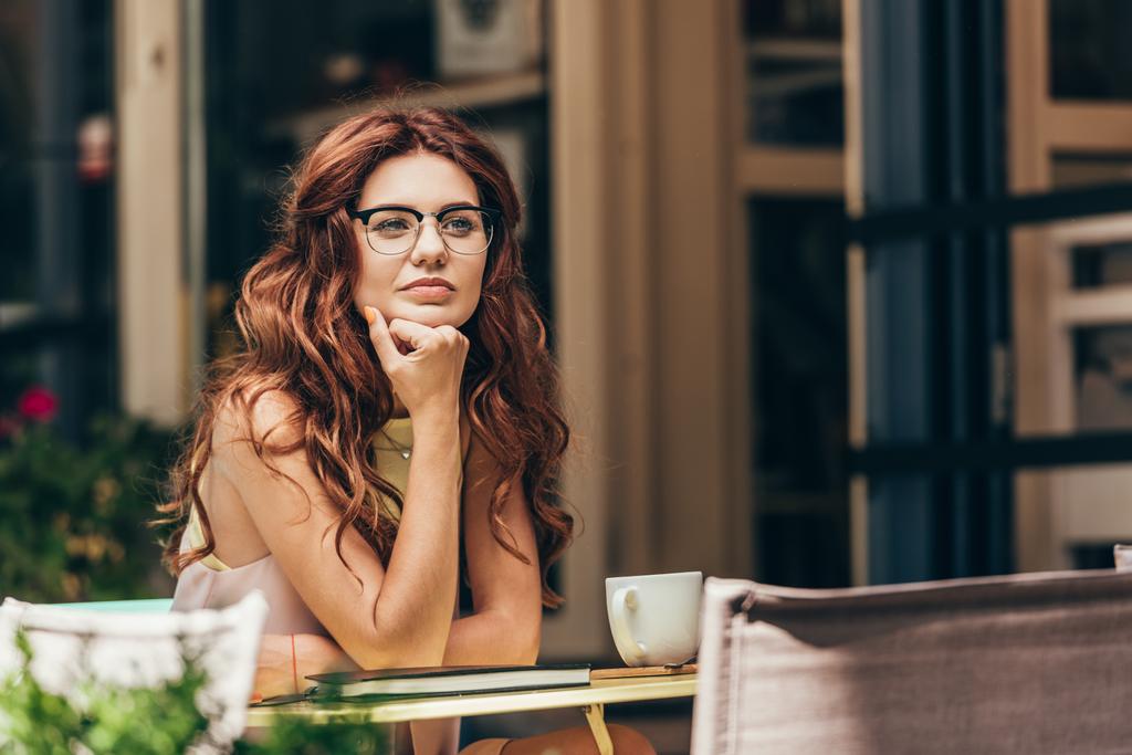 一杯のコーヒーとカフェでノートをテーブルで眼鏡の物思いにふける女性実業家の肖像 - 写真・画像