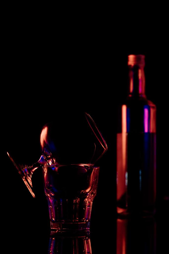 κλείνω πάνω θέα του μπουκαλιού και γυαλιά με sambuca αλκοολούχου ποτού σε μαύρο φόντο - Φωτογραφία, εικόνα